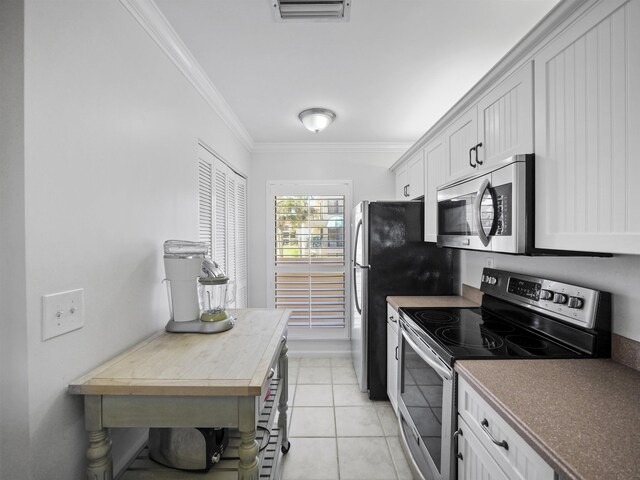 kitchen with white cabinetry, light tile patterned floors, ornamental molding, and stainless steel appliances