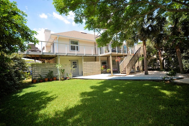 back of house featuring a balcony, a patio area, and a lawn