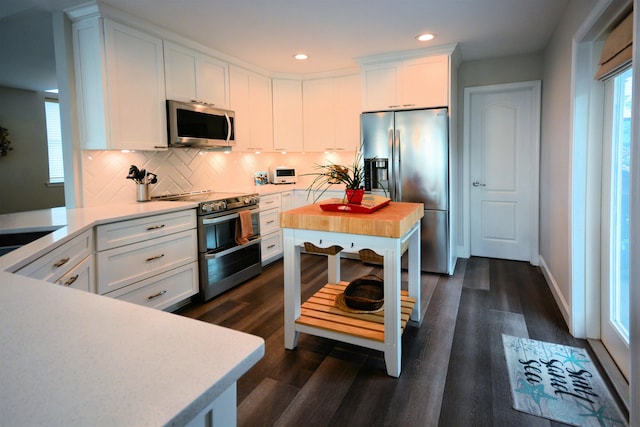 kitchen with white cabinets, stainless steel appliances, decorative backsplash, and dark wood-type flooring