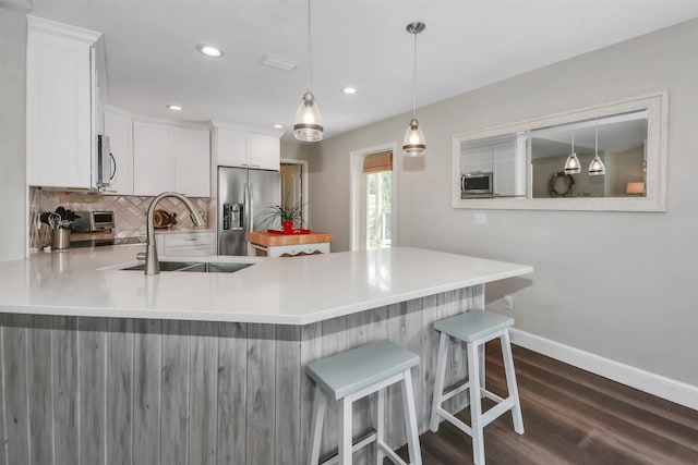 kitchen with sink, appliances with stainless steel finishes, white cabinets, pendant lighting, and dark wood-type flooring