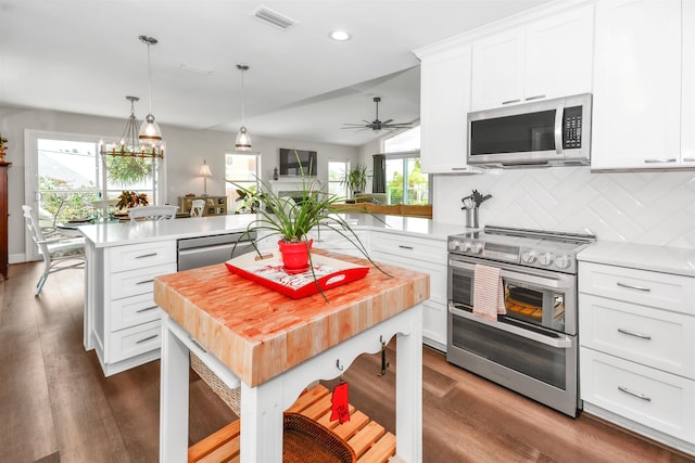 kitchen featuring appliances with stainless steel finishes, a center island, white cabinetry, lofted ceiling, and tasteful backsplash