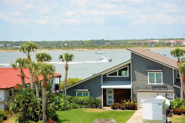 view of front of property with a front lawn, a garage, and a water view