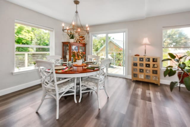 dining area with dark wood-type flooring and an inviting chandelier