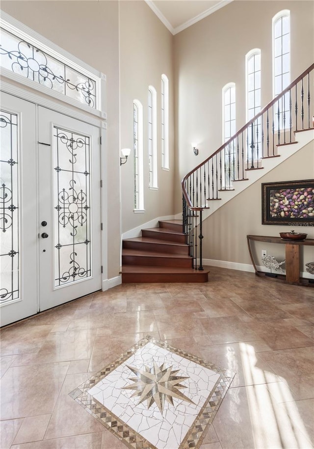 entryway featuring baseboards, a high ceiling, stairs, and crown molding