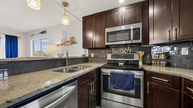 kitchen featuring sink, hanging light fixtures, stainless steel appliances, tasteful backsplash, and light stone counters