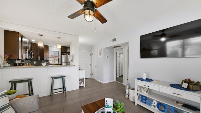 living room featuring ceiling fan, dark tile patterned floors, and a textured ceiling