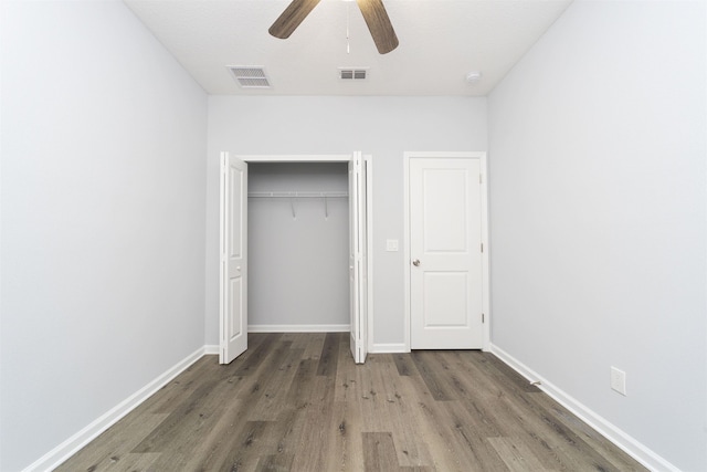 unfurnished bedroom featuring ceiling fan, dark hardwood / wood-style floors, and a closet