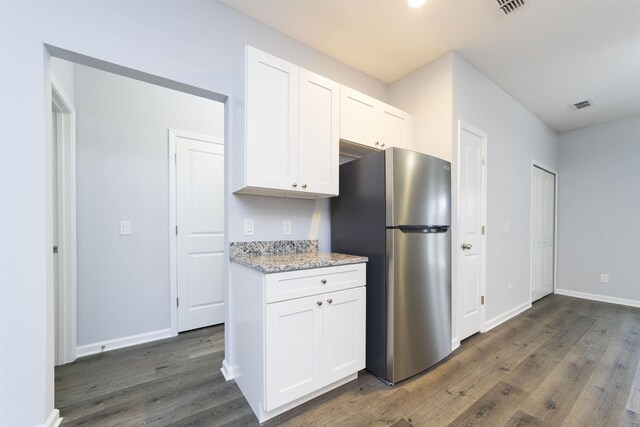 679 Coral Cir, Saint Augustine, FL 32080 - kitchen with freestanding refrigerator, dark wood-type flooring, white cabinets, and light stone counters