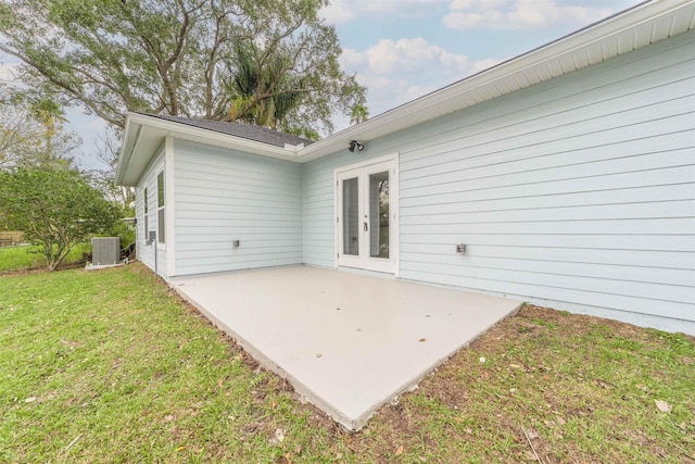 rear view of property with french doors, a patio, cooling unit, and a lawn