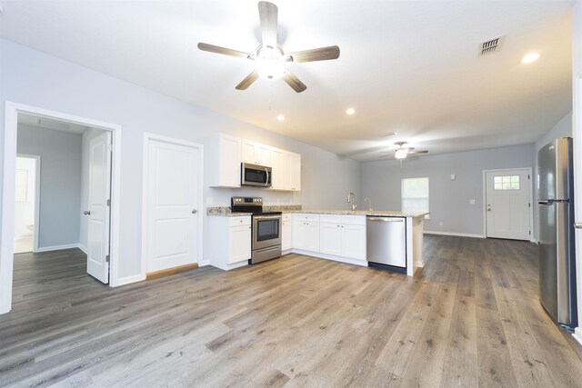 679 Coral Cir, Saint Augustine, FL 32080 - kitchen featuring stainless steel appliances, a ceiling fan, a peninsula, light wood-style floors, and white cabinets