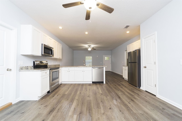 kitchen featuring hardwood / wood-style flooring, white cabinetry, kitchen peninsula, and appliances with stainless steel finishes