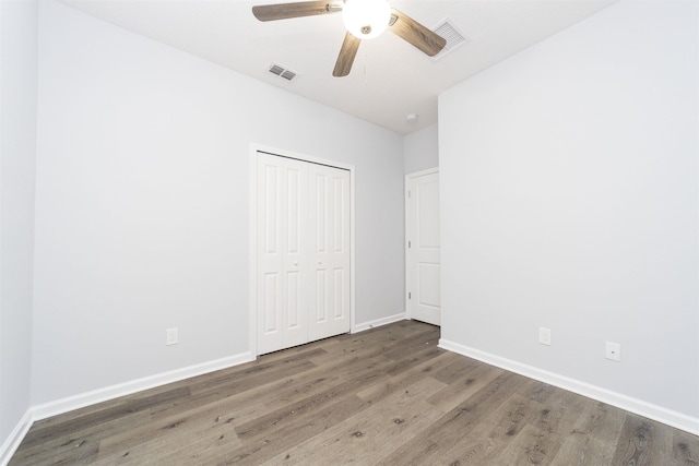 unfurnished bedroom with ceiling fan, a closet, and dark hardwood / wood-style floors