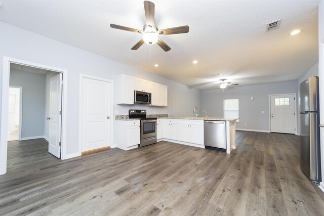 679 Coral Cir, Saint Augustine, FL 32080 - kitchen with appliances with stainless steel finishes, a ceiling fan, a peninsula, wood finished floors, and white cabinetry