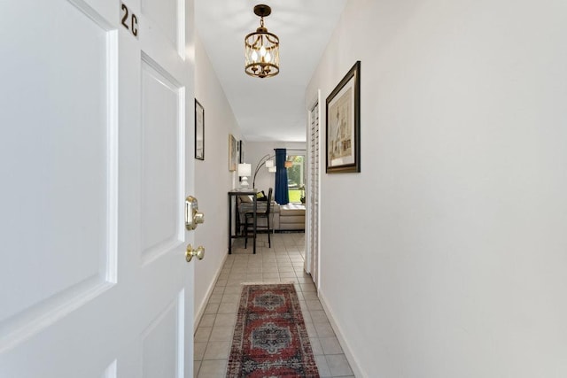 hallway with light tile patterned floors and an inviting chandelier