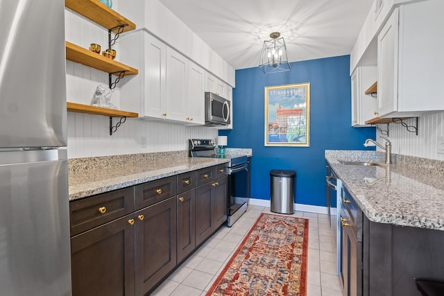 kitchen with light stone countertops, appliances with stainless steel finishes, sink, and white cabinets