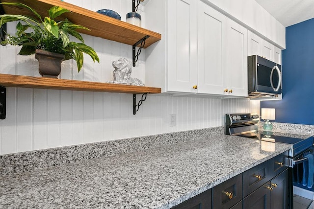 kitchen with stainless steel appliances, light stone countertops, and white cabinets