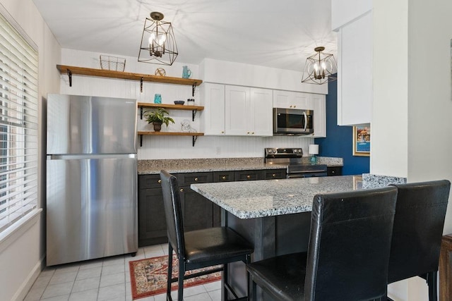 kitchen featuring appliances with stainless steel finishes, a wealth of natural light, hanging light fixtures, and white cabinets