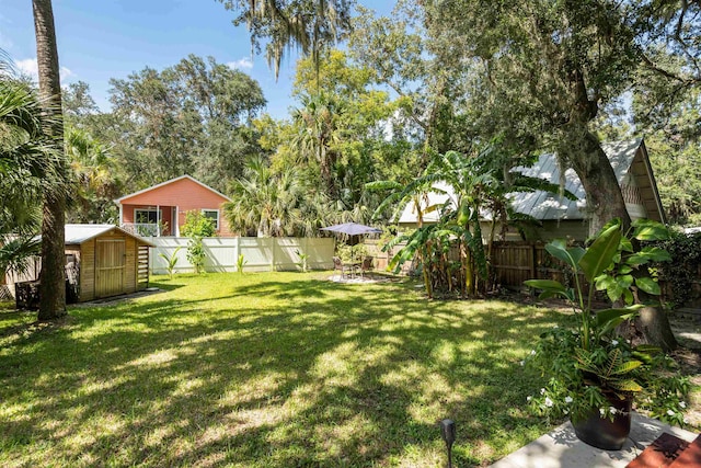 view of yard featuring an outdoor structure, a fenced backyard, and a shed
