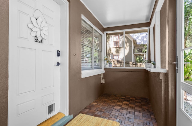 unfurnished sunroom featuring plenty of natural light and ornamental molding