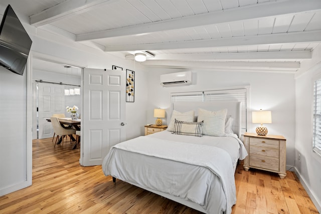 bedroom featuring an AC wall unit, baseboards, beam ceiling, and light wood finished floors
