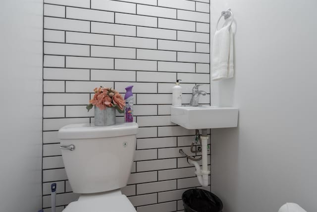 bathroom featuring a sink, toilet, and tile walls