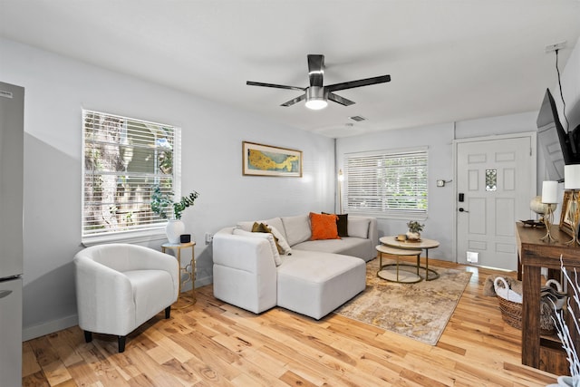 living area with baseboards, ceiling fan, visible vents, and light wood-style flooring