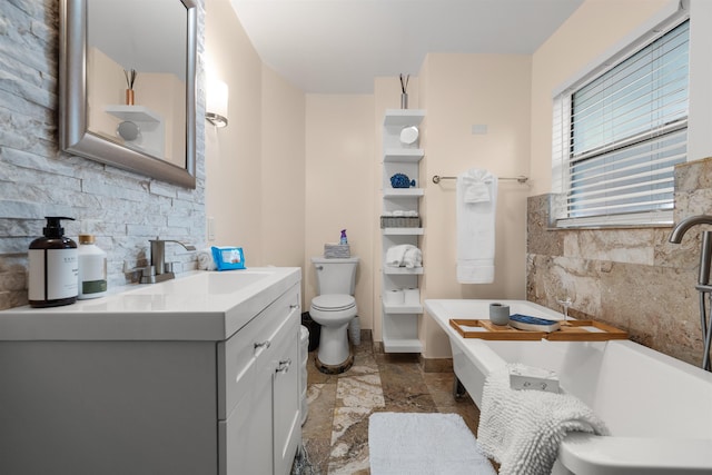 bathroom with a freestanding bath, vanity, and toilet