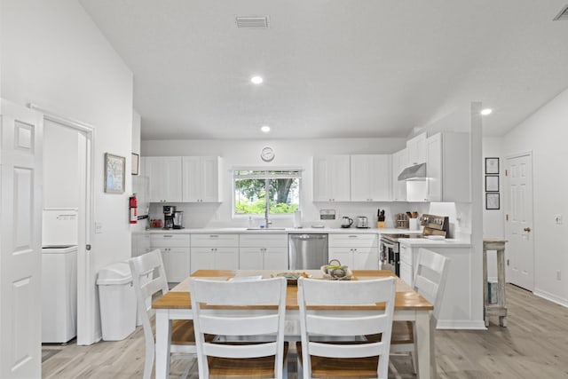 110 Dory Rd, Saint Augustine, FL 32086 - kitchen with appliances with stainless steel finishes, under cabinet range hood, light wood-style flooring, white cabinetry, and recessed lighting