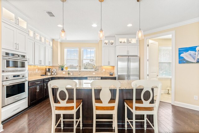 kitchen featuring a center island, stainless steel appliances, white cabinetry, and tasteful backsplash