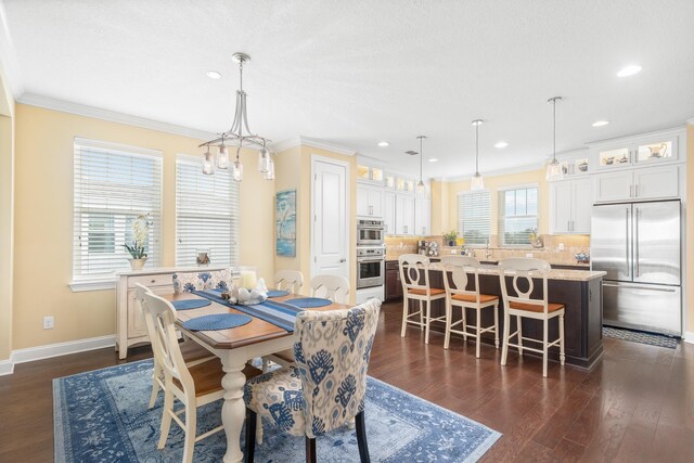 dining area featuring a healthy amount of sunlight, dark hardwood / wood-style flooring, an inviting chandelier, and ornamental molding