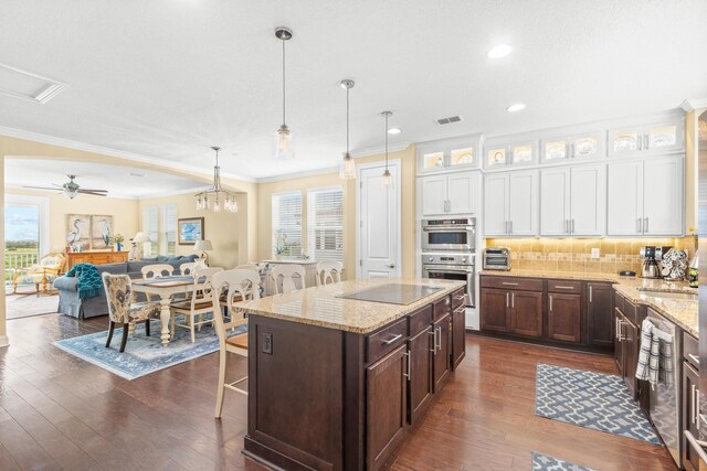 kitchen featuring hanging light fixtures, crown molding, a breakfast bar, white cabinets, and ceiling fan with notable chandelier