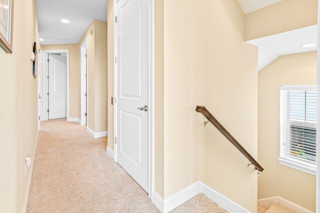 corridor with light carpet and lofted ceiling