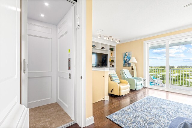 sitting room with hardwood / wood-style flooring, built in features, and ornamental molding