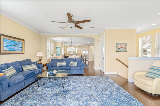 living room with ceiling fan with notable chandelier, dark hardwood / wood-style flooring, and crown molding