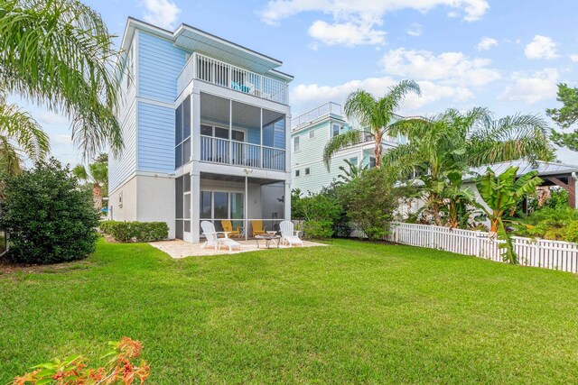 back of house featuring a balcony, a patio area, and a lawn