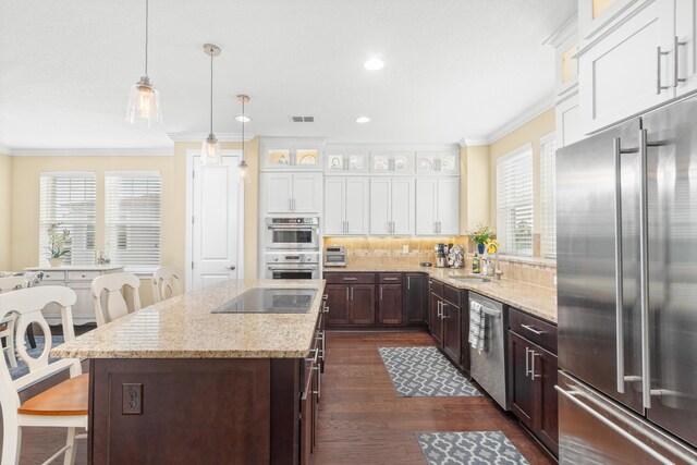 kitchen with dark wood-type flooring, hanging light fixtures, a kitchen island, stainless steel appliances, and white cabinets