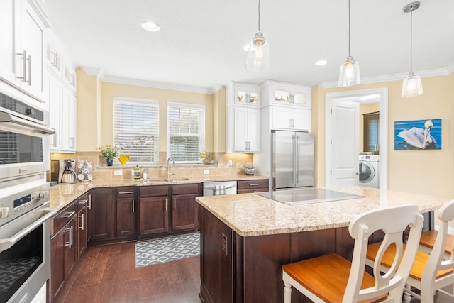 kitchen with dark wood-type flooring, sink, a kitchen island, stainless steel appliances, and washer / clothes dryer