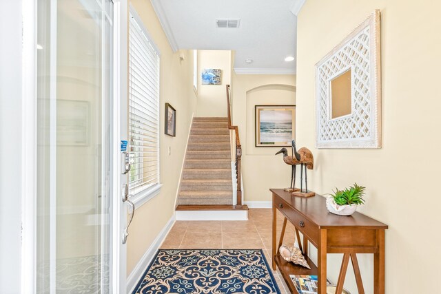 entrance foyer featuring a wealth of natural light, crown molding, and light tile patterned floors