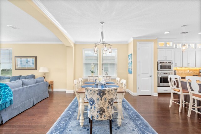 dining area with a healthy amount of sunlight, dark hardwood / wood-style floors, an inviting chandelier, and crown molding