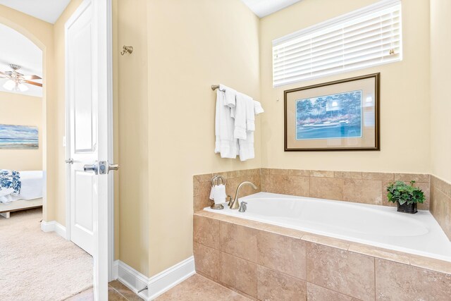 bathroom with tiled bath and ceiling fan