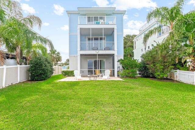 back of property with a lawn, a patio area, and a balcony