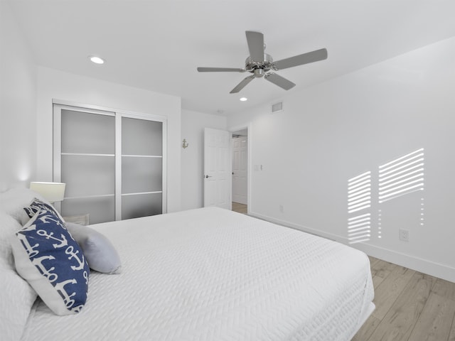 bedroom with ceiling fan, a closet, and light hardwood / wood-style floors