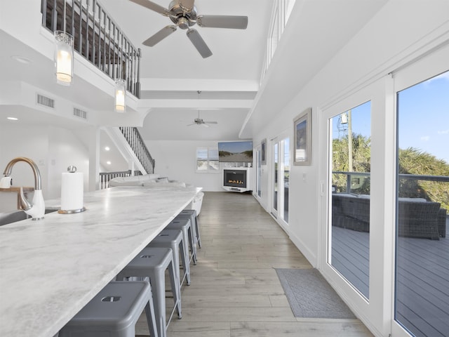 kitchen with a breakfast bar area, ceiling fan, a high ceiling, wood-type flooring, and pendant lighting