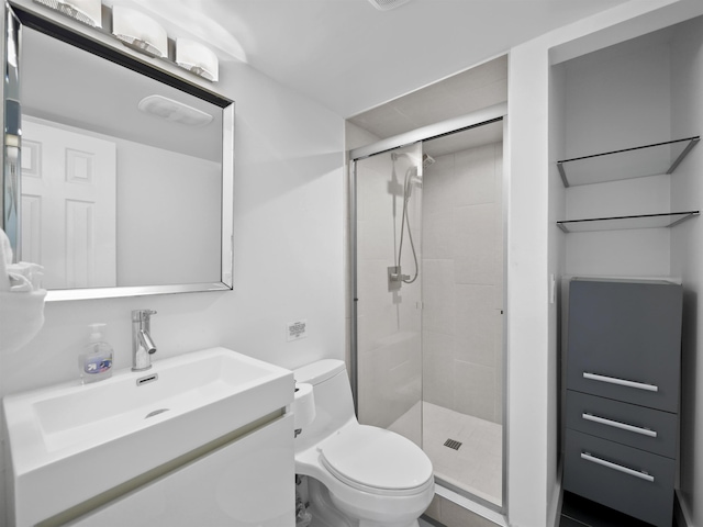 bathroom featuring a shower with shower door, toilet, and vanity