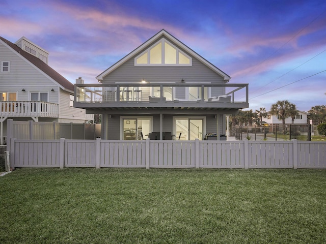 back house at dusk with a wooden deck and a yard