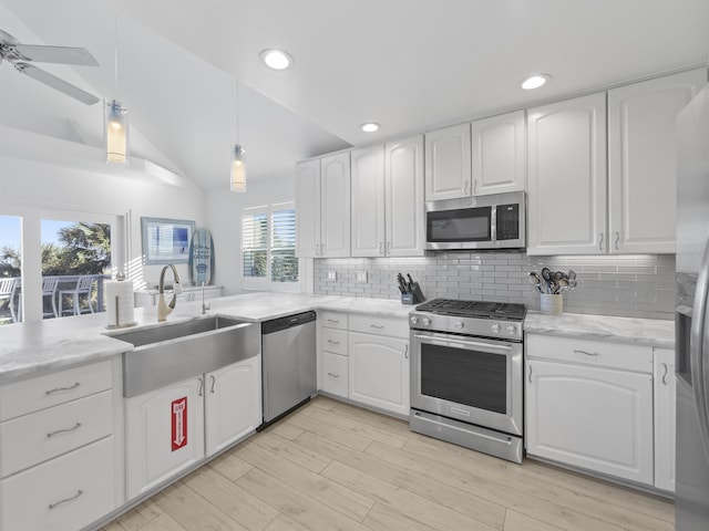 kitchen with vaulted ceiling, appliances with stainless steel finishes, white cabinetry, and sink