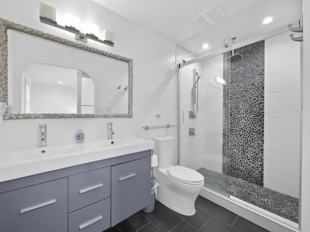 bathroom featuring toilet, tile patterned flooring, a shower with shower door, and vanity