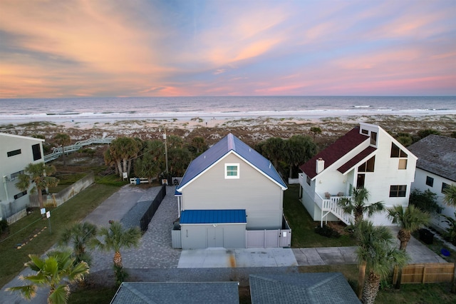 aerial view at dusk with a water view and a beach view