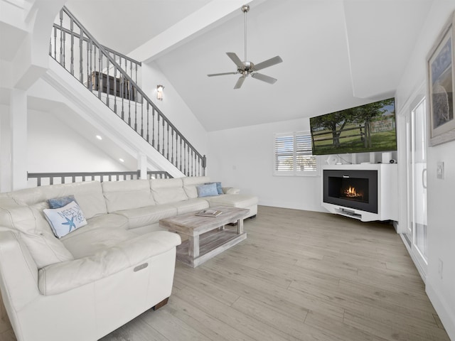 living room with ceiling fan, beam ceiling, a high ceiling, and hardwood / wood-style floors