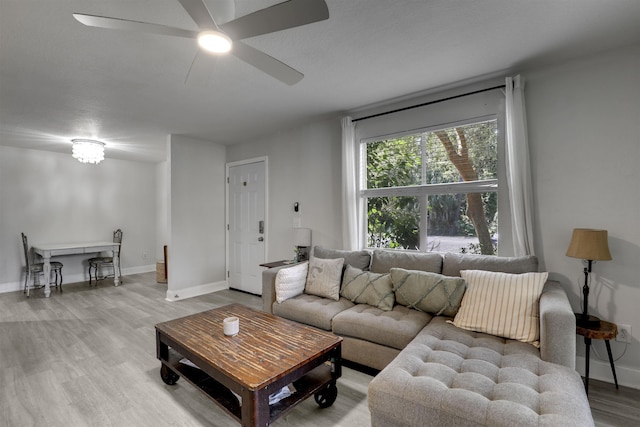 living area featuring ceiling fan, baseboards, and wood finished floors